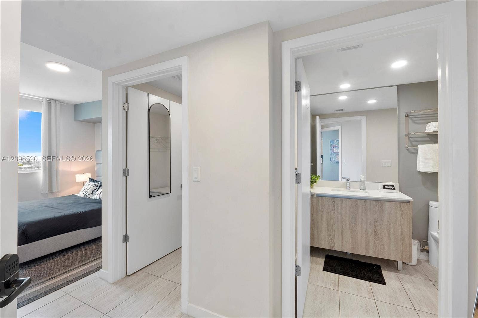 Bathroom featuring a wood-finish vanity with a light-toned countertop, recessed ceiling lighting, and tile flooring