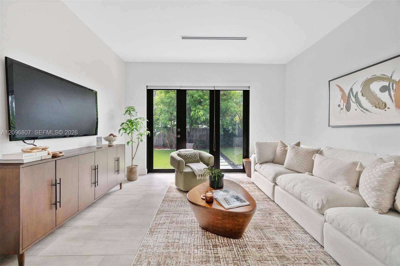 Neutral-toned interior featuring large-format tile flooring, recessed ceiling lighting, and black-framed French doors