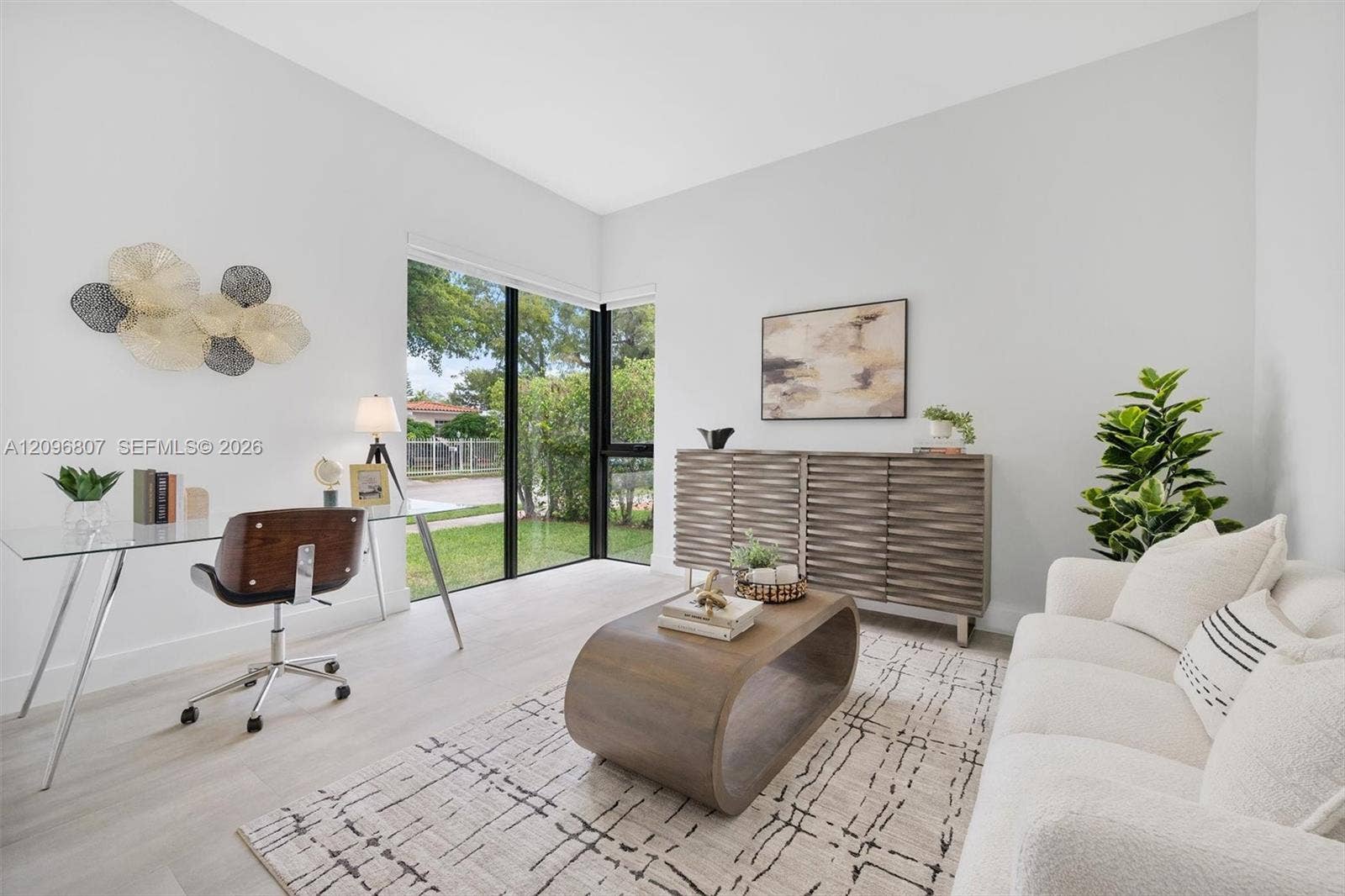 Neutral interior space featuring high ceilings, wood-finish flooring, and floor-to-ceiling corner windows with black frames