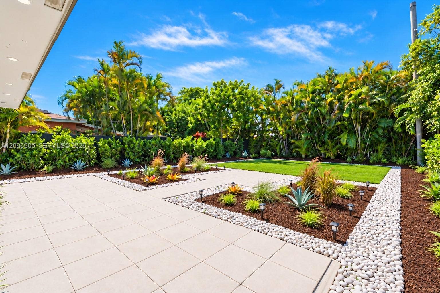Expansive outdoor area featuring a large patio, manicured lawn, and mature landscaping