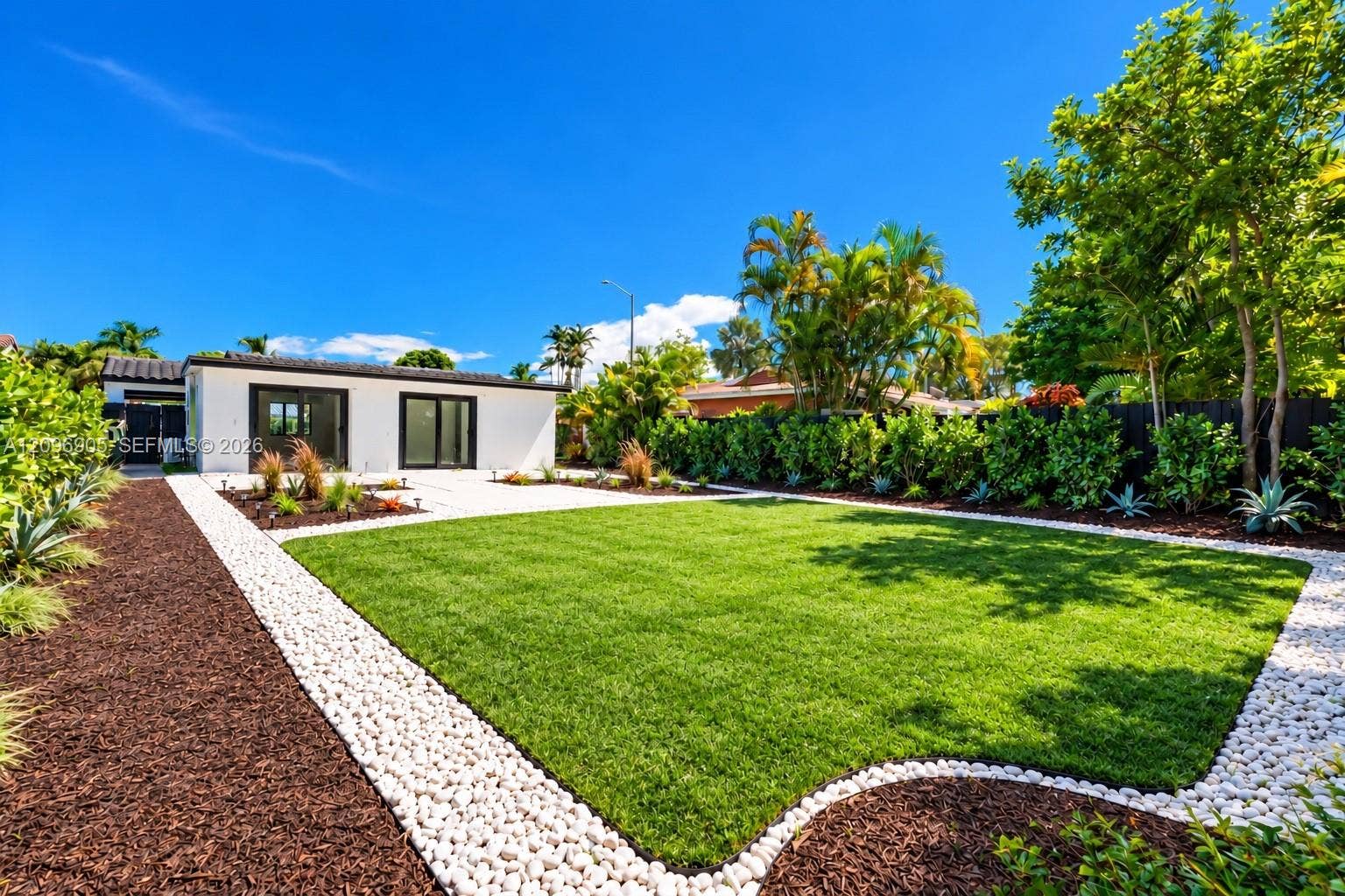 Expansive green lawn framed by a white pebble path and dark mulch