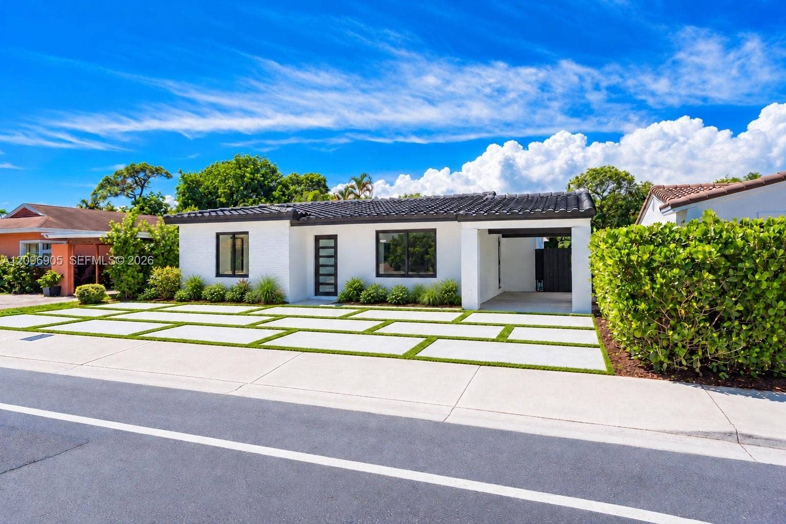 Contemporary exterior with a white stucco finish, dark tile roof, and black-framed windows