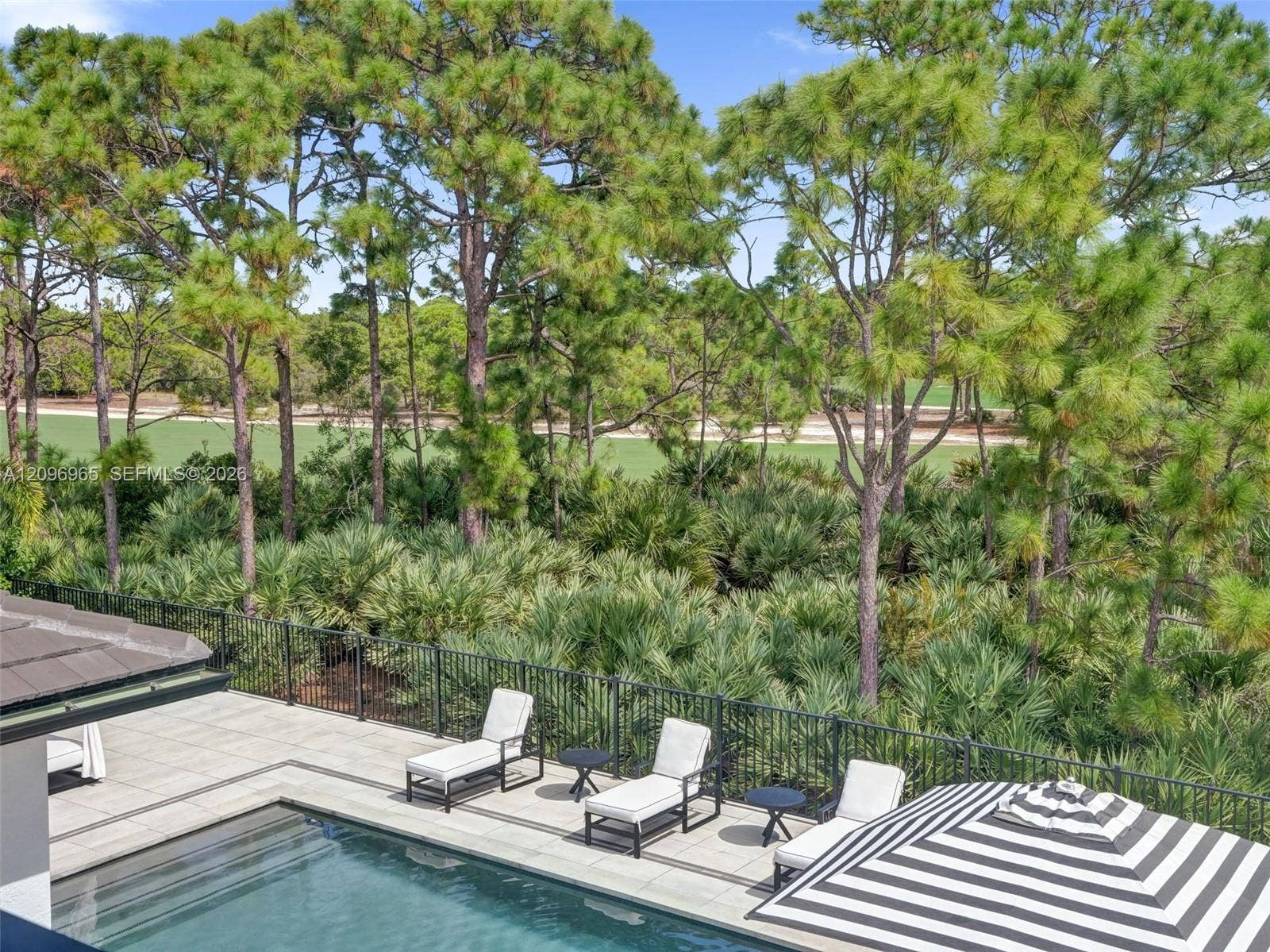 10157 SE Sandpine Lane, Hobe Sound, FL 33455 Outdoor terrace featuring a swimming pool, stone-finish decking, and black metal perimeter fencing