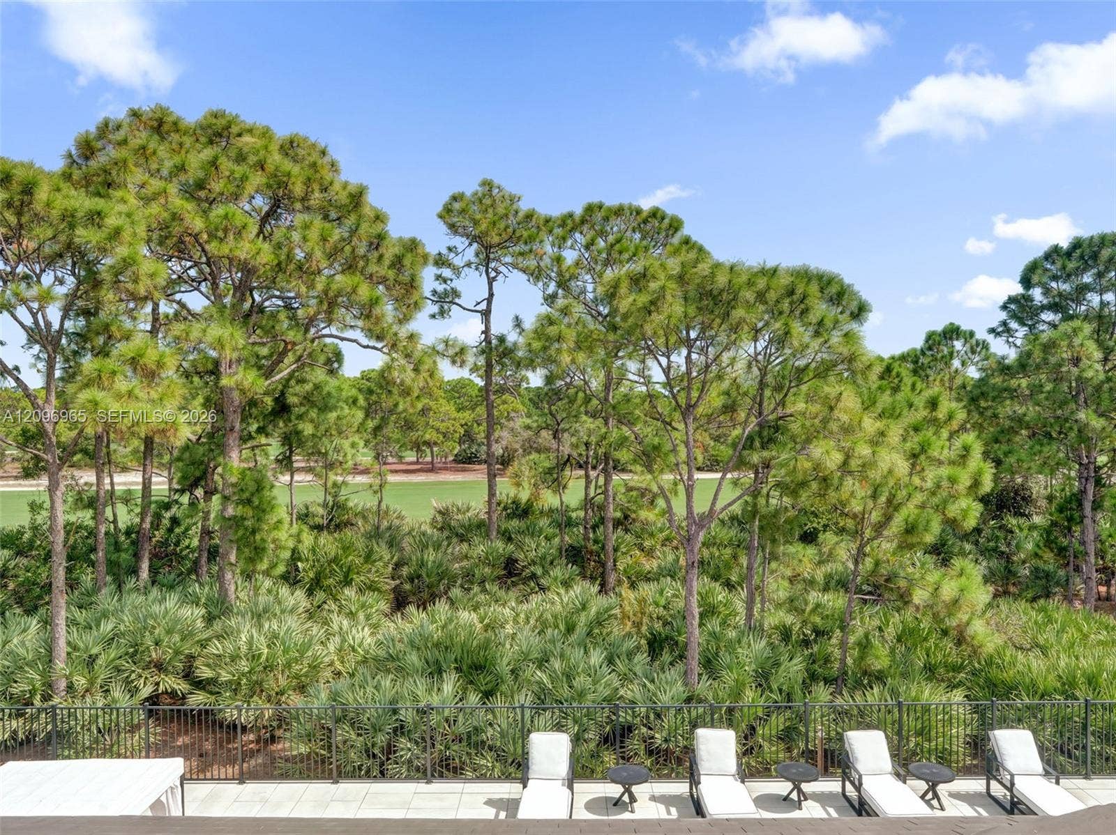 10157 SE Sandpine Lane, Hobe Sound, FL 33455 Elevated terrace featuring stone tile flooring and black metal railing, overlooking mature trees and open green space