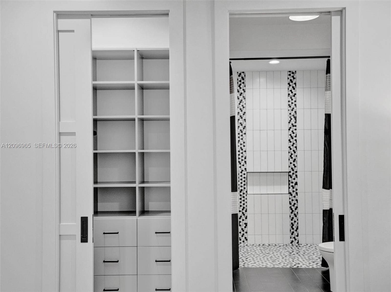 10157 SE Sandpine Lane, Hobe Sound, FL 33455 Built-in cabinetry featuring open shelving and soft-close drawers, sliding pocket doors, walk-in shower with vertical mosaic accent tile, and recessed lighting