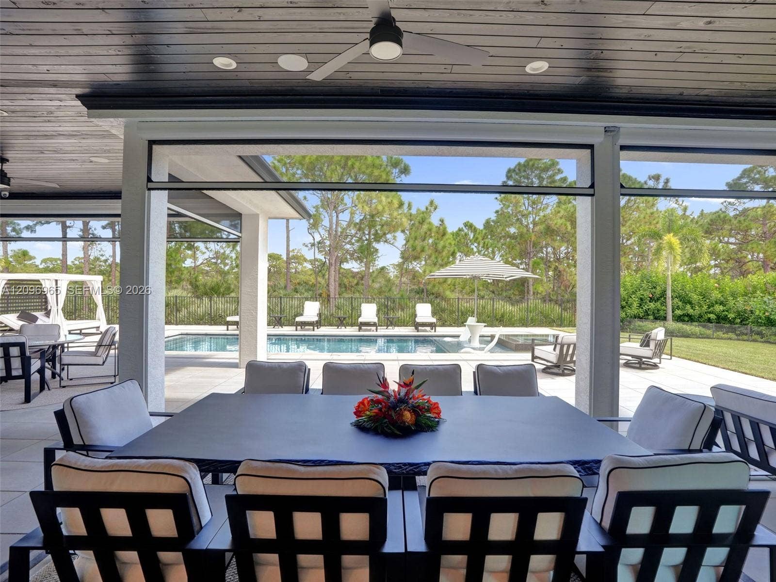 10157 SE Sandpine Lane, Hobe Sound, FL 33455 Covered patio featuring a stained wood plank ceiling, recessed lighting, a modern ceiling fan, retractable screens, and tile flooring