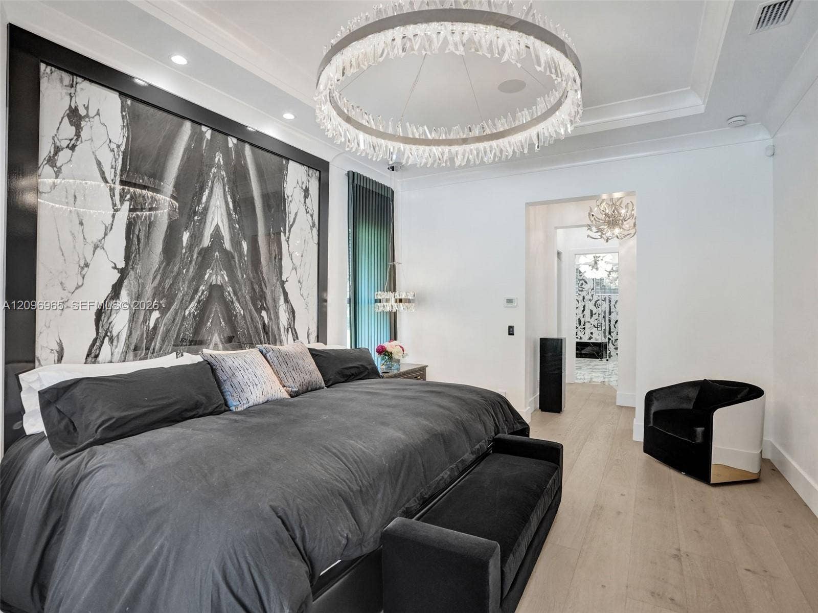 10157 SE Sandpine Lane, Hobe Sound, FL 33455 Full-height dramatic stone feature wall with integrated dark frame, circular tiered crystal chandelier, tray ceiling with recessed lighting, and wood-finish flooring