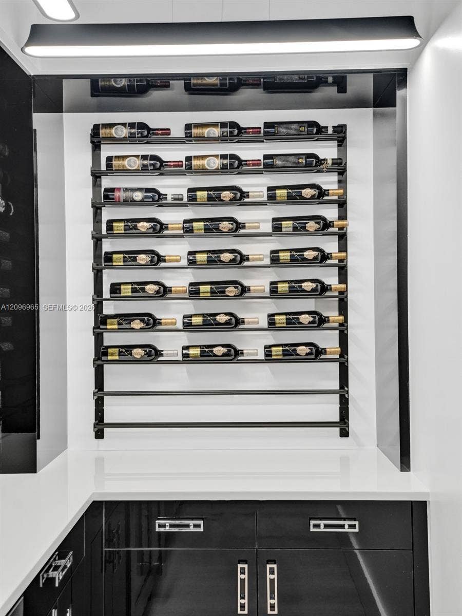 10157 SE Sandpine Lane, Hobe Sound, FL 33455 Custom wine display featuring horizontal metal racking, high-gloss black cabinetry, white countertops, and integrated linear lighting