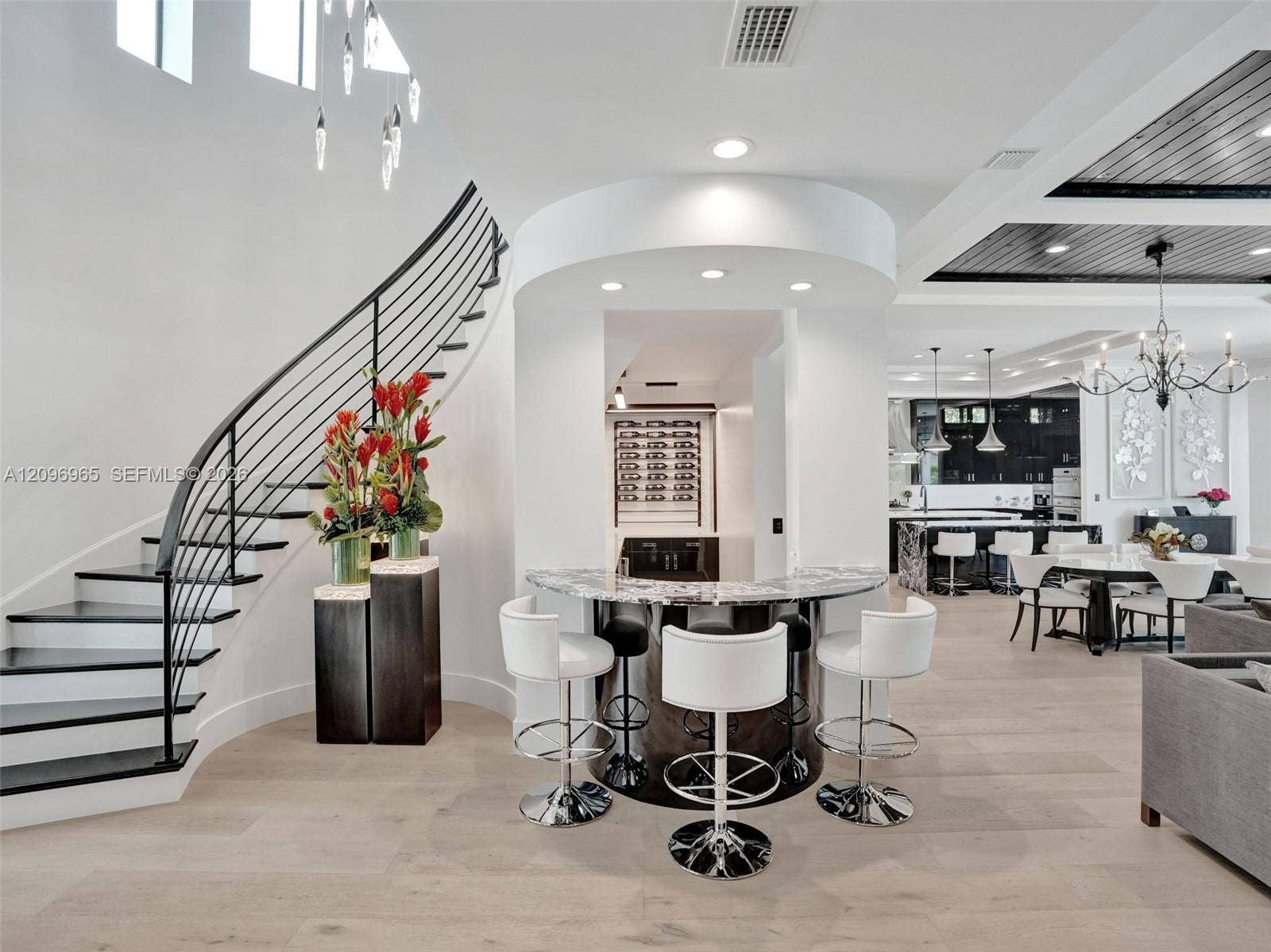 10157 SE Sandpine Lane, Hobe Sound, FL 33455 Curved staircase with black metal railing, built-in wet bar featuring stone-surface countertop, recessed lighting, plank-style flooring, and coffered ceiling with dark wood-finish detail