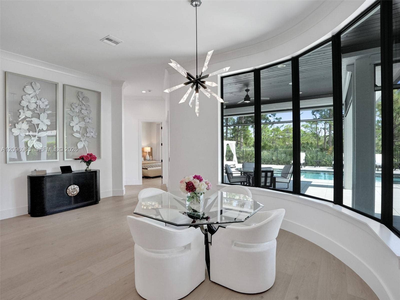 10157 SE Sandpine Lane, Hobe Sound, FL 33455 Curved floor-to-ceiling windows with black frames, wood-finish flooring, modern starburst chandelier, and crown molding