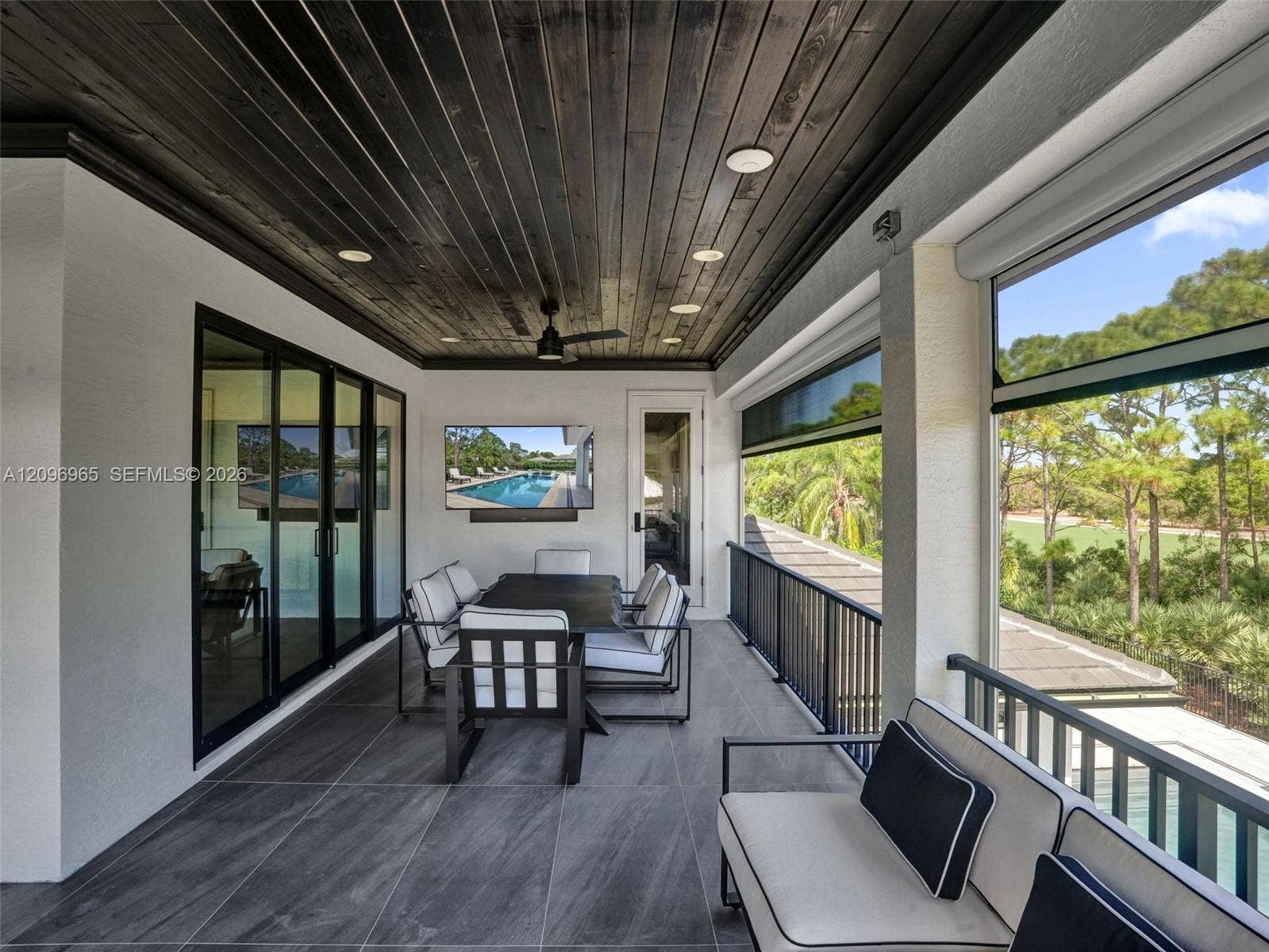 10157 SE Sandpine Lane, Hobe Sound, FL 33455 Covered terrace featuring dark wood-plank ceiling, large-format tile flooring, recessed lighting, ceiling fan, and black metal railing