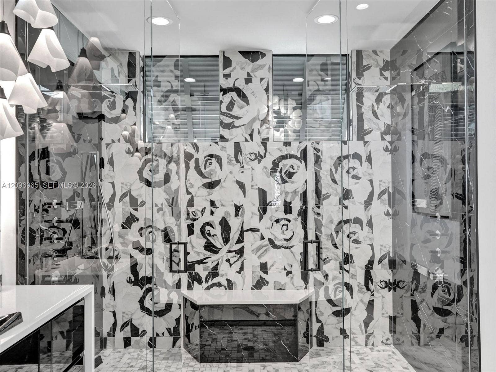 10157 SE Sandpine Lane, Hobe Sound, FL 33455 Walk-in shower enclosure featuring large-format patterned tile, a built-in bench with a stone-surface top, frameless glass panels, and recessed ceiling lighting