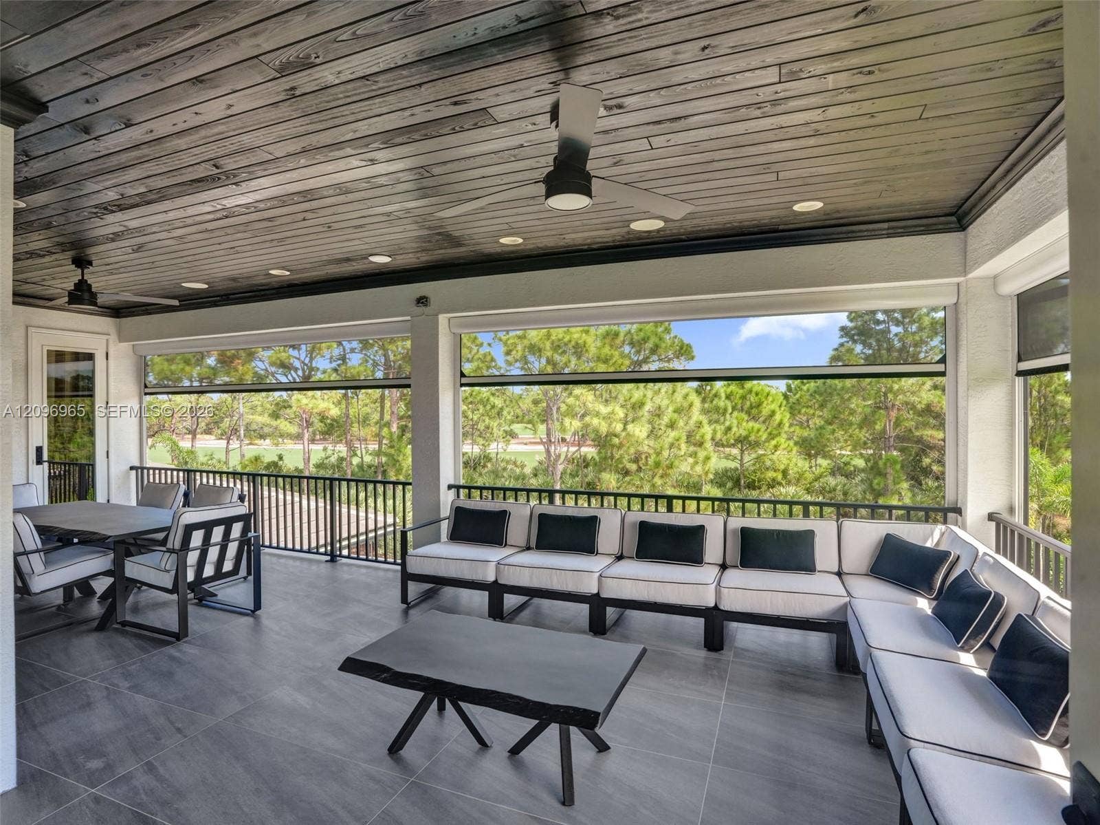 10157 SE Sandpine Lane, Hobe Sound, FL 33455 Covered lanai featuring large-format tile flooring, wood-plank ceiling, recessed lighting, ceiling fans, and black metal railings