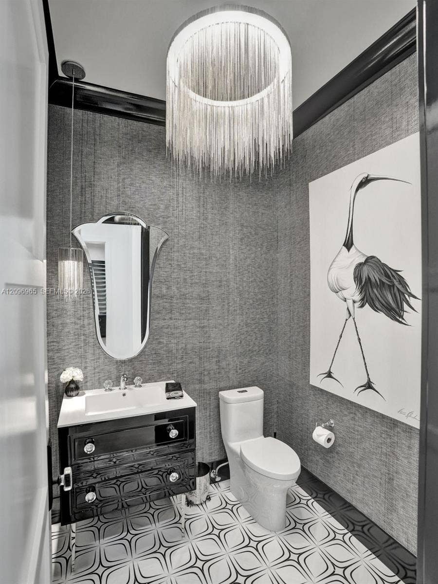 10157 SE Sandpine Lane, Hobe Sound, FL 33455 Custom vanity featuring integrated sink and glossy finish, distinctive geometric floor tile, textured wall covering, and statement chain-link drum pendant lighting