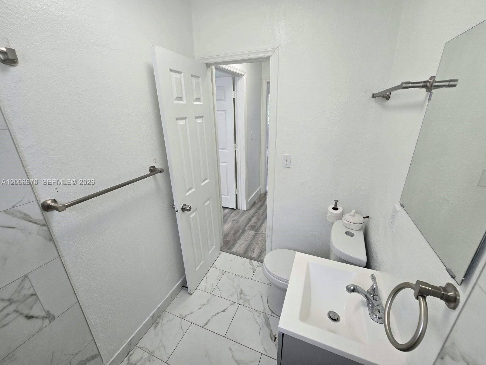 535 NW 7th Street, #12, Miami, Miami, FL 33136 Bathroom featuring large-format tile flooring with a marble-finish, a vanity with a white rectangular basin and metal fixtures, and a shower surround with marble-finish tiling
