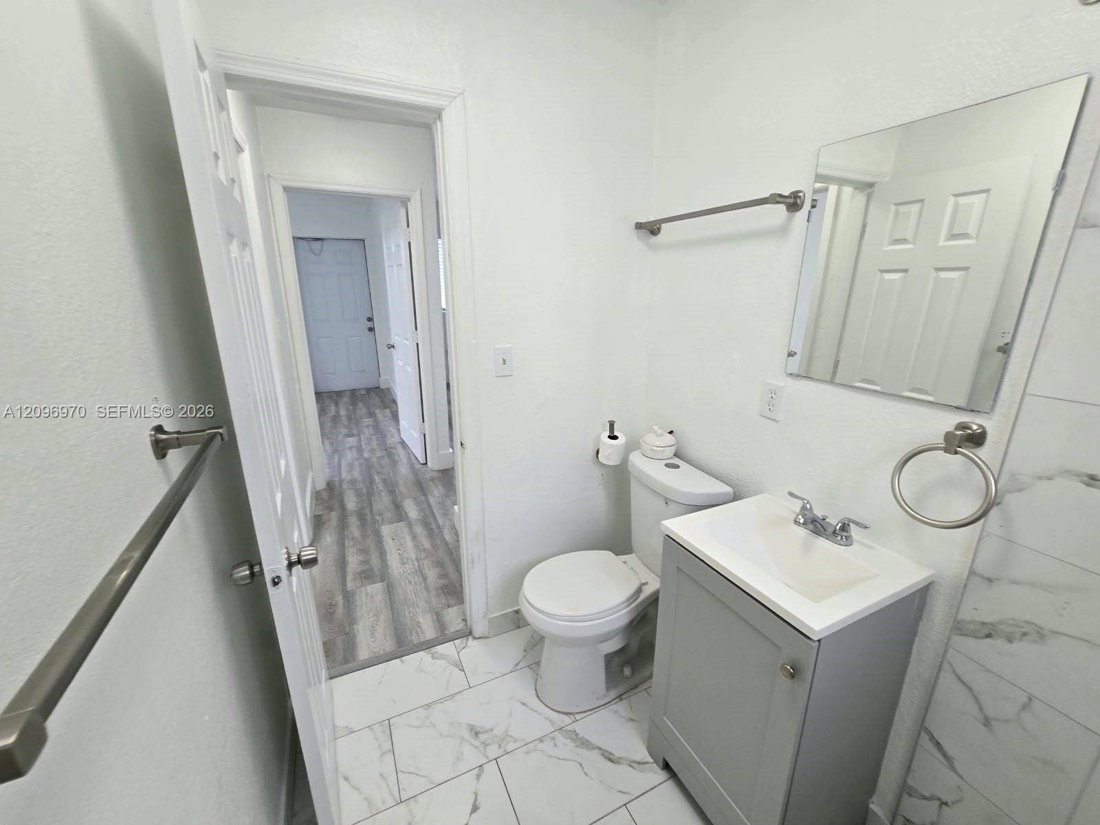 535 NW 7th Street, #12, Miami, Miami, FL 33136 Bathroom featuring large-format tile flooring with a veined pattern, vanity with a rectangular sink, brushed nickel fixtures, and a wall-mounted mirror