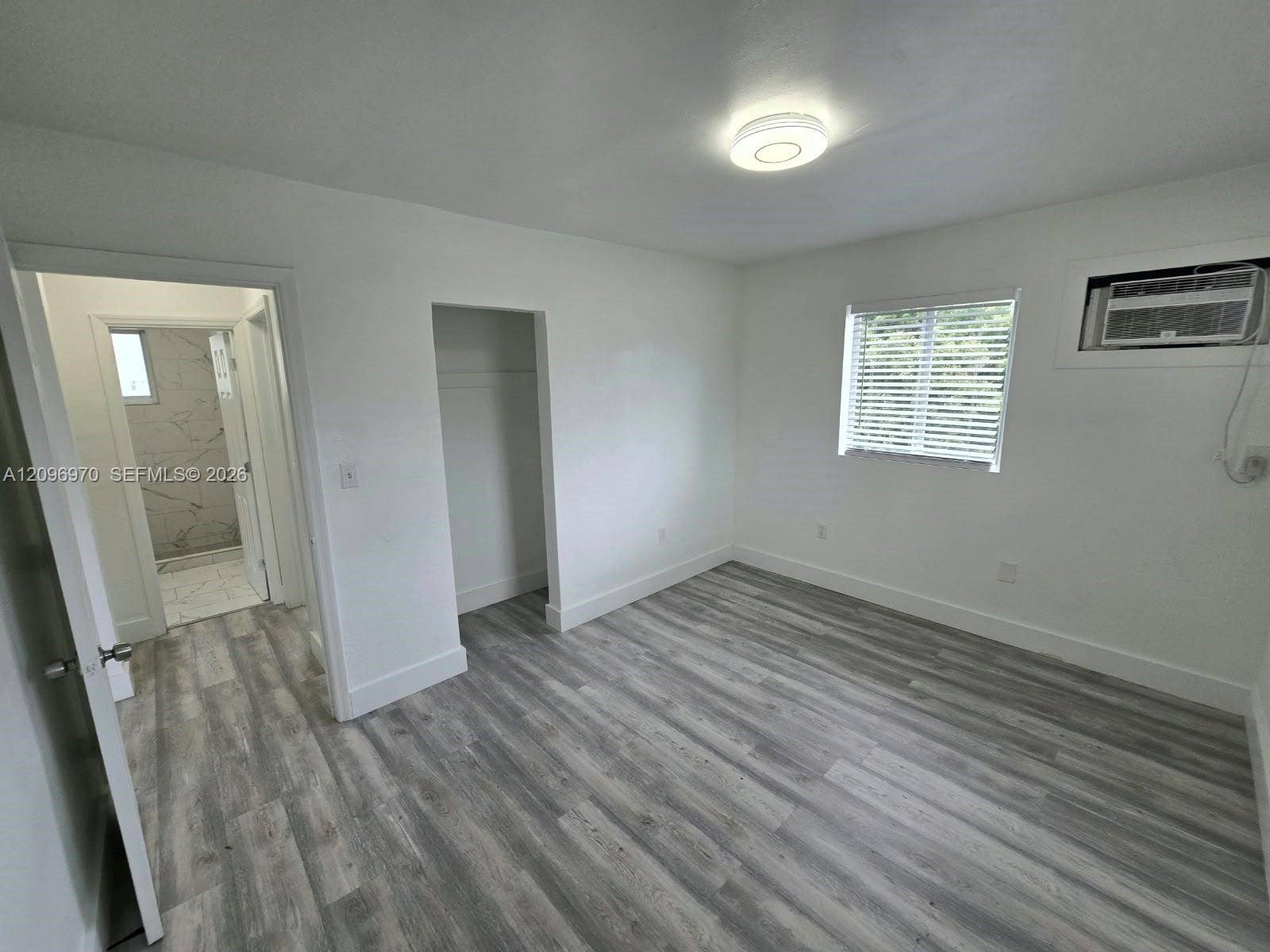 535 NW 7th Street, #12, Miami, Miami, FL 33136 Room featuring wood-finish flooring, recessed LED lighting, a window with horizontal blinds, and a built-in wall air conditioning unit