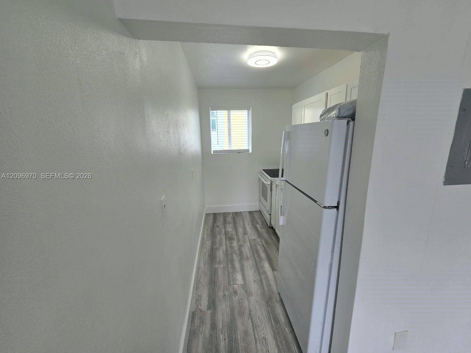 535 NW 7th Street, #12, Miami, Miami, FL 33136 Kitchen featuring wood-finish flooring, white cabinetry, a top-freezer refrigerator, a range, and a flush-mount ceiling light fixture