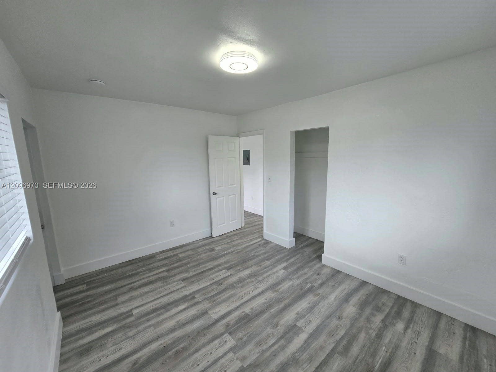 535 NW 7th Street, #12, Miami, Miami, FL 33136 Neutral-toned interior space featuring wood-finish flooring, white walls, a flush-mount ceiling light fixture, a paneled swing door, and an open-entry closet