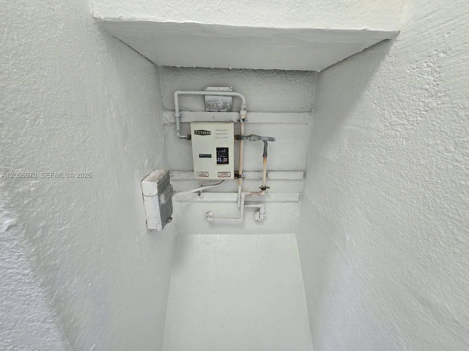 535 NW 7th Street, #12, Miami, Miami, FL 33136 Electric tankless water heater with dedicated electrical disconnect and exposed plumbing conduits housed within a recessed utility alcove