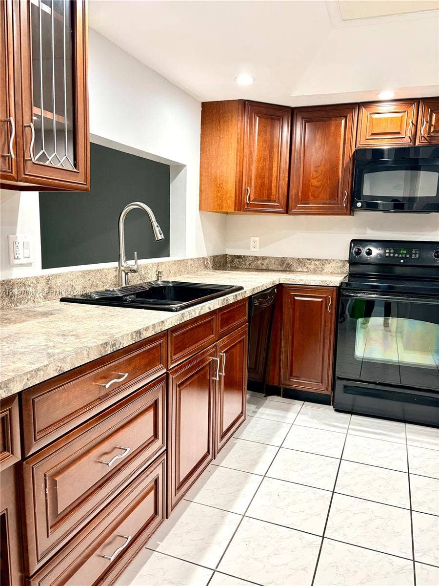 3271 Coral Springs Drive, #2, Coral Springs, Coral Springs, FL 33065 Kitchen featuring warm-tone wood cabinetry, black integrated appliances, a high-arc pull-down faucet, and neutral laminate countertops
