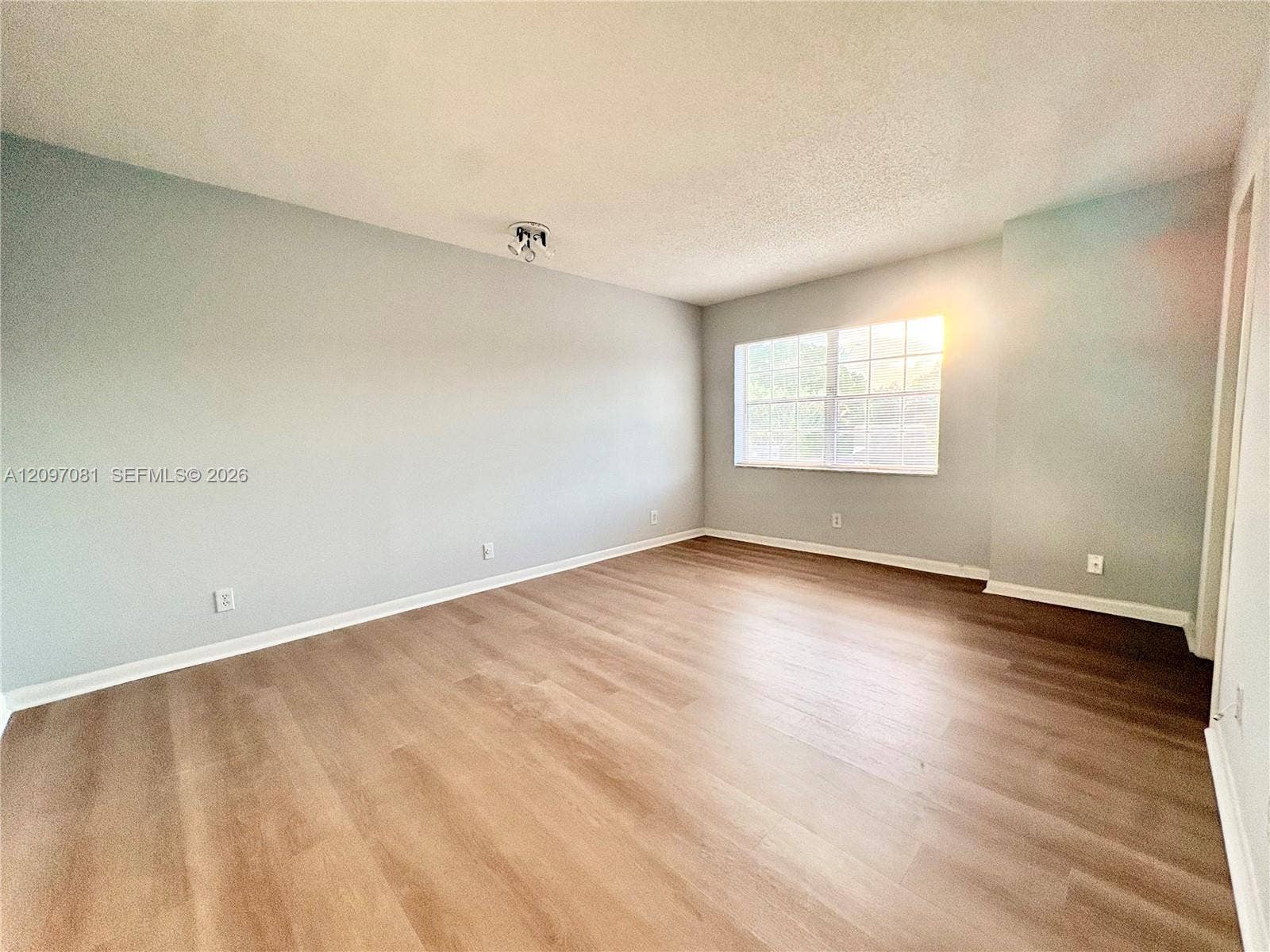 3271 Coral Springs Drive, #2, Coral Springs, Coral Springs, FL 33065 Neutral-toned interior space featuring wood-finish flooring, multi-pane window, and overhead ceiling-mounted lighting