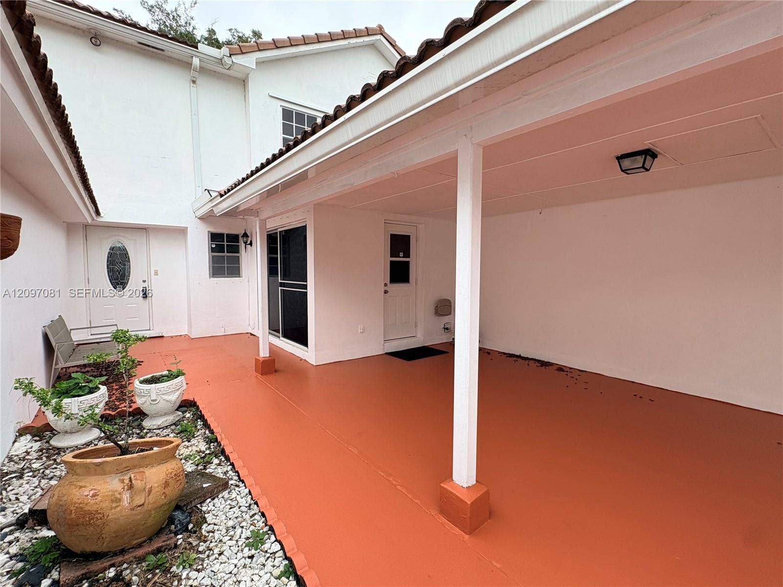 3271 Coral Springs Drive, #2, Coral Springs, Coral Springs, FL 33065 Covered patio featuring a solid-surface floor, two exterior entry doors, and a gravel-lined landscape bed