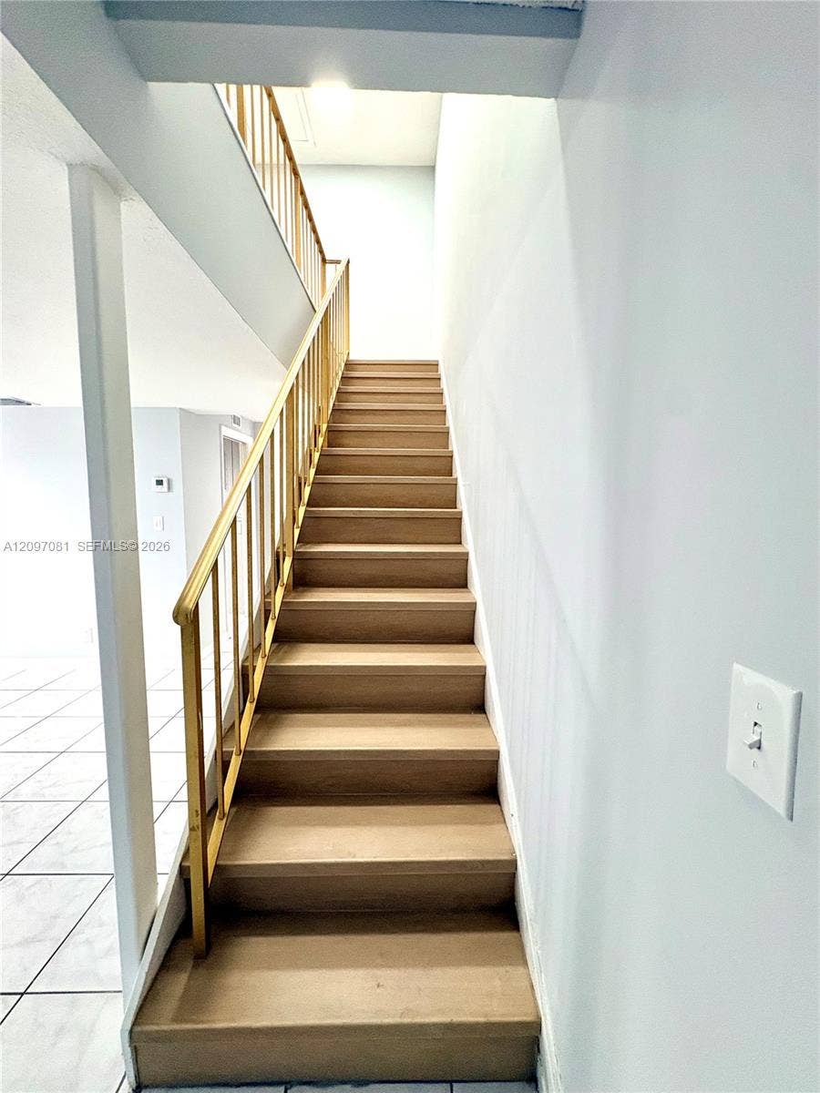 3271 Coral Springs Drive, #2, Coral Springs, Coral Springs, FL 33065 Staircase featuring wood-finish treads and a metal vertical-bar railing