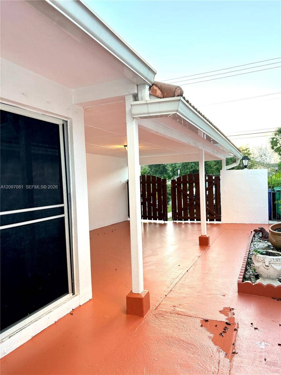 3271 Coral Springs Drive, #2, Coral Springs, Coral Springs, FL 33065 Covered patio featuring a painted concrete surface, support columns, a sliding glass door, and a decorative garden border