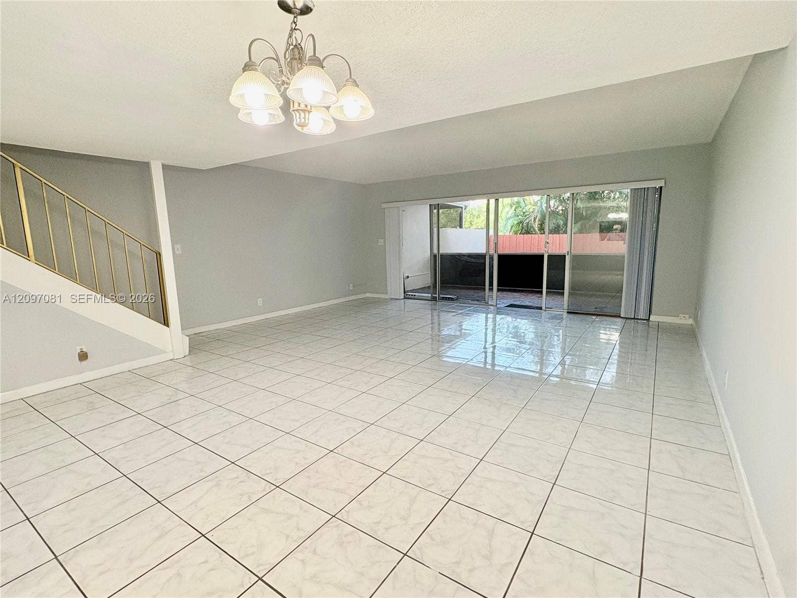 3271 Coral Springs Drive, #2, Coral Springs, Coral Springs, FL 33065 Open floor plan featuring large-format tile flooring, a multi-pane glass sliding door, and a multi-arm chandelier with brushed-metal finish