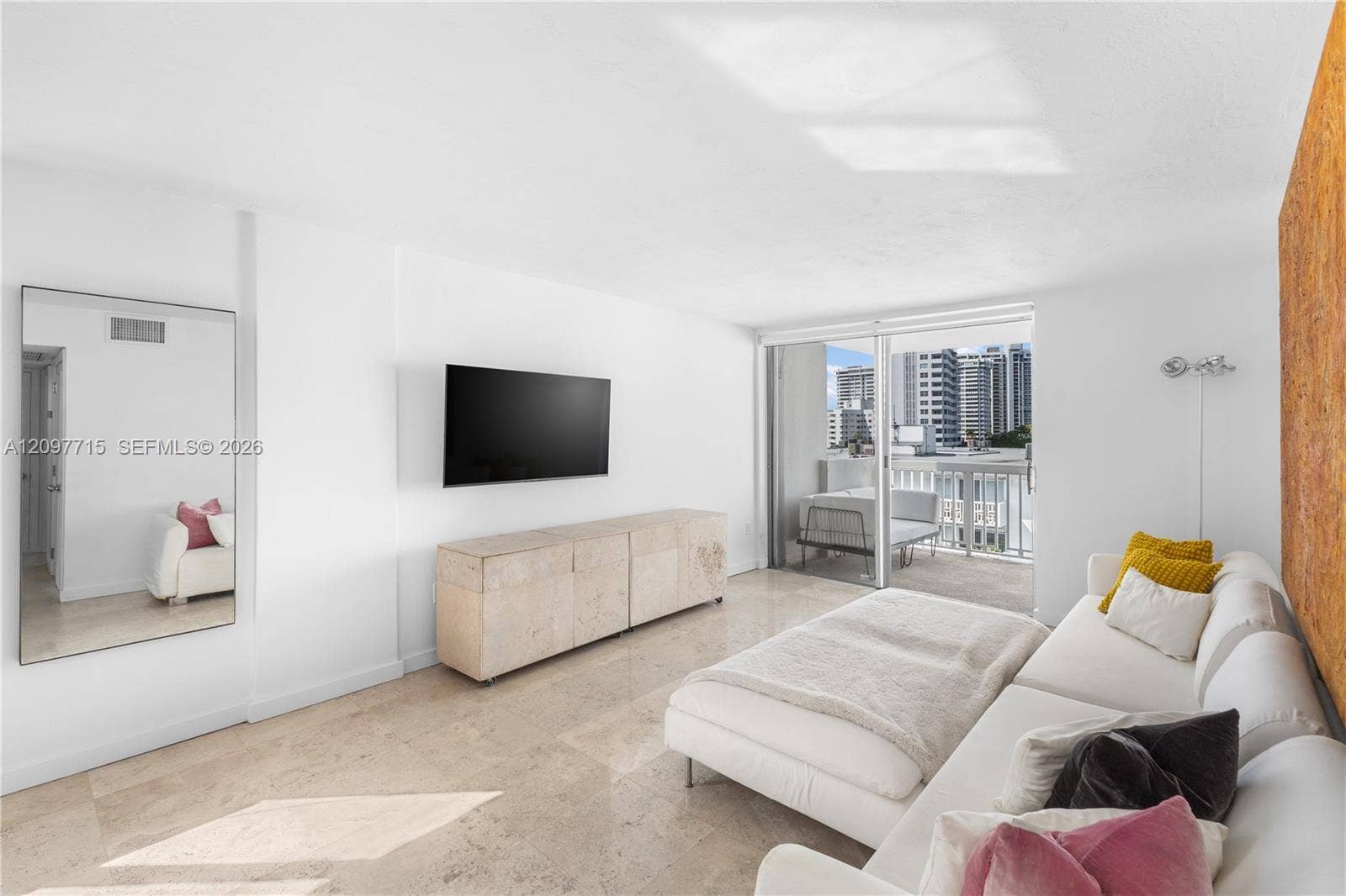 Bright living area featuring stone tile flooring, a wall-mounted television, and a built-in media console