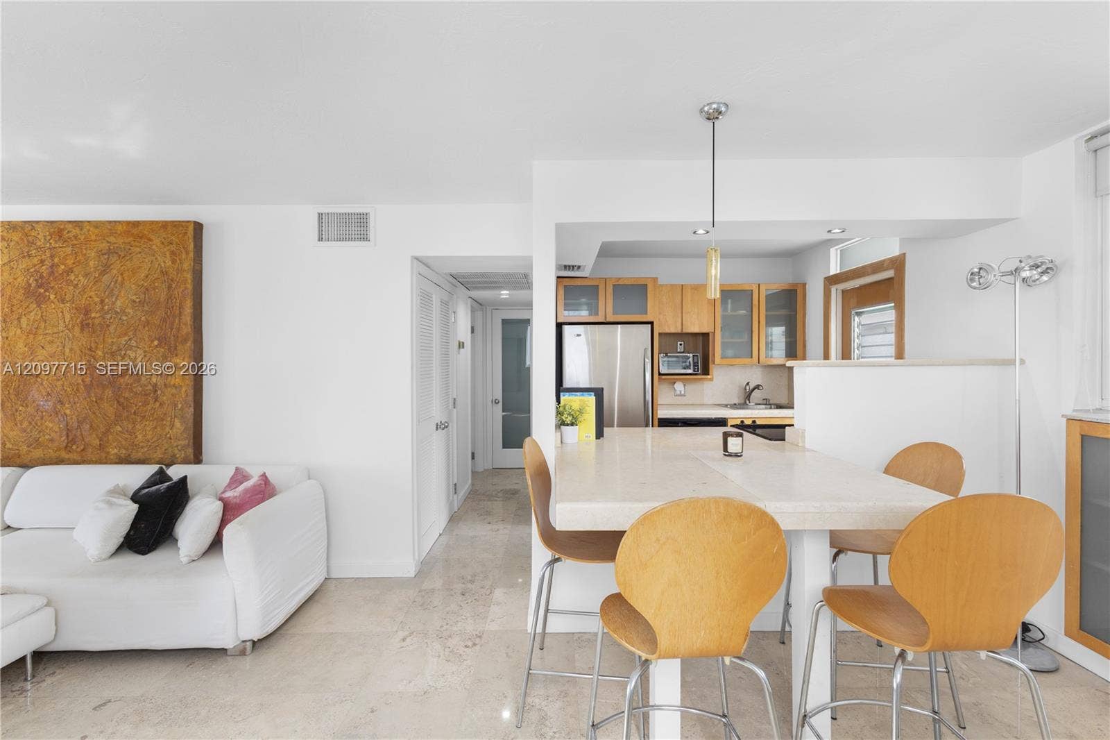 Open-concept layout featuring stone flooring, a kitchen with wood-finish cabinetry, stainless steel appliances, and a peninsula with seating