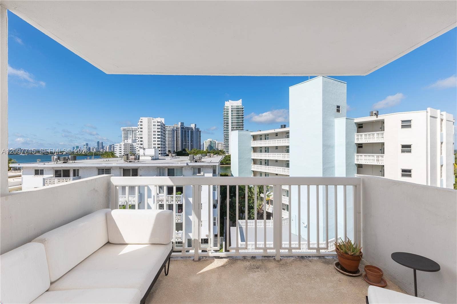Expansive balcony with concrete flooring, white painted railings, and distant cityscape