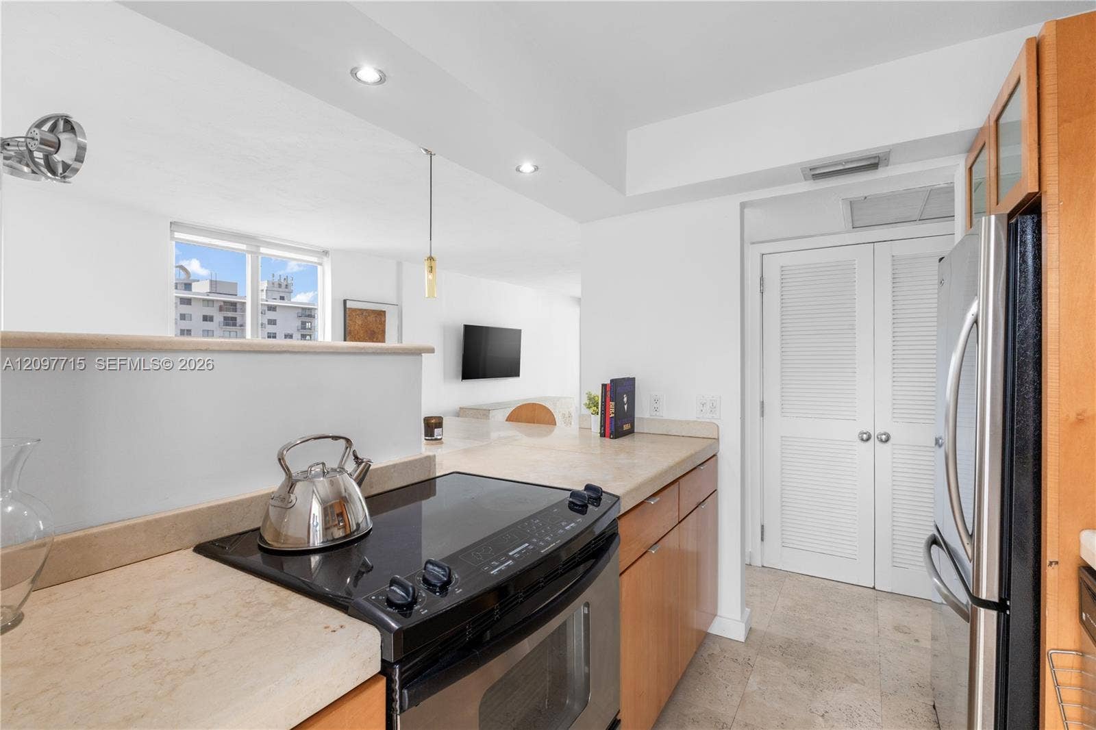 Contemporary kitchen featuring a built-in electric range, stainless steel refrigerator, wood-finish cabinetry, and recessed lighting