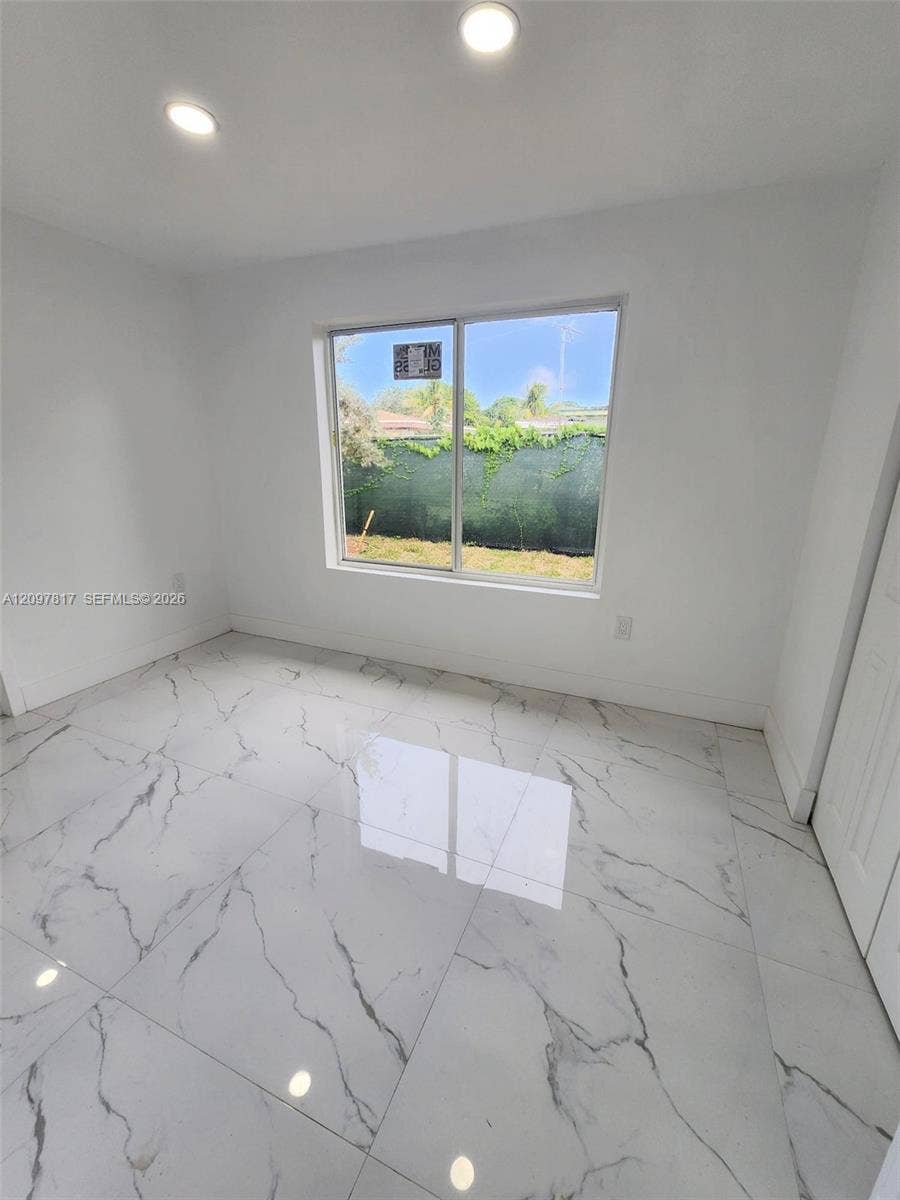 Large-format stone-finish floor tiles featuring veined detailing, recessed ceiling lighting, and a large horizontal sliding window