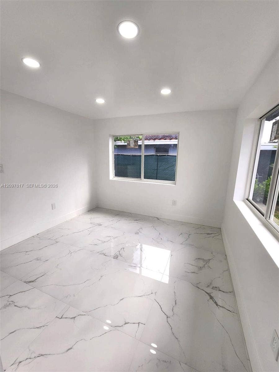 Polished stone-finish tile flooring, recessed ceiling lighting, and large-format sliding windows
