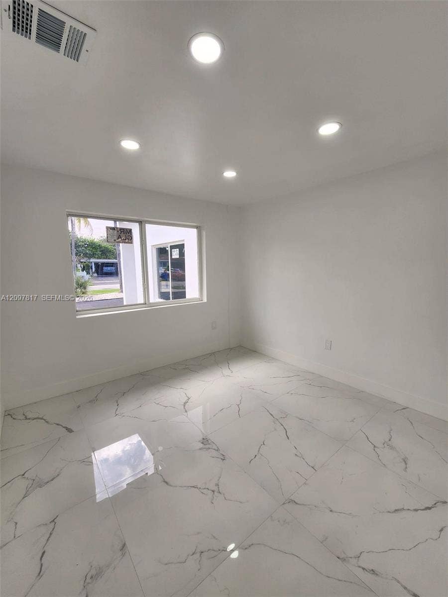 Large-format, light-toned flooring with decorative veining, recessed ceiling lighting, and a single-pane horizontal window