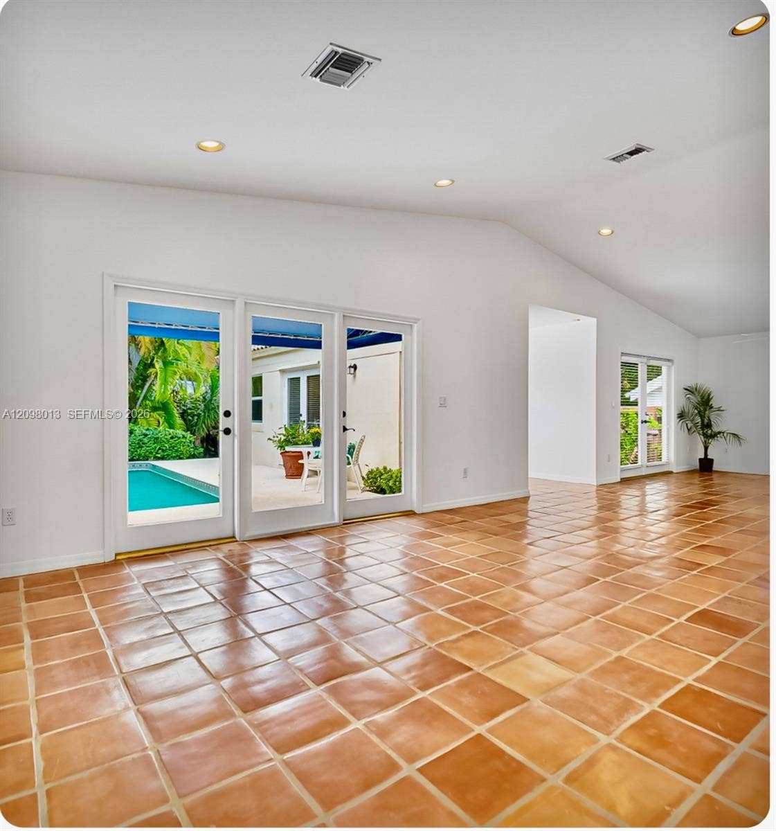 Living area featuring vaulted ceilings, French doors providing outdoor access