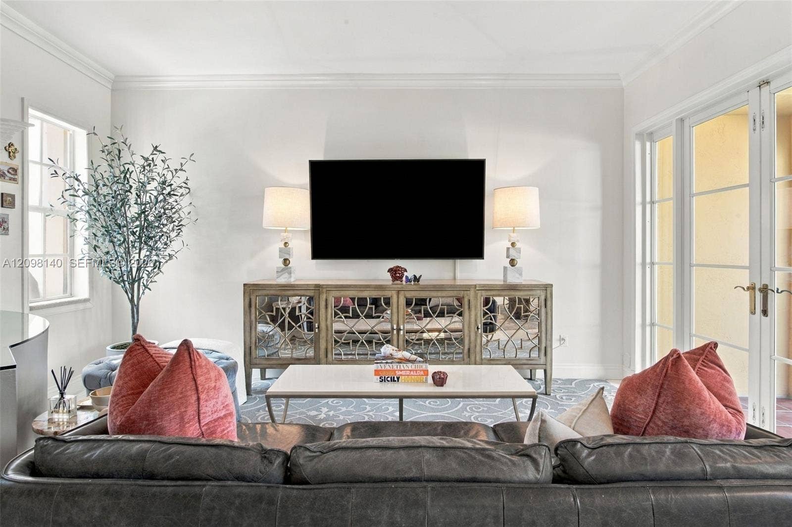 Living area featuring crown molding, multi-pane glass doors, and large windows with recessed framing