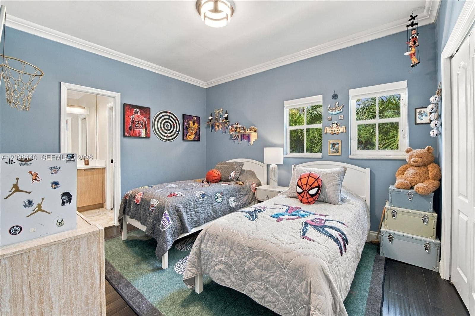 Bedroom featuring dark wood-finish flooring, crown molding, double-hung windows with exterior mullions, and an attached en-suite bathroom with a built-in vanity