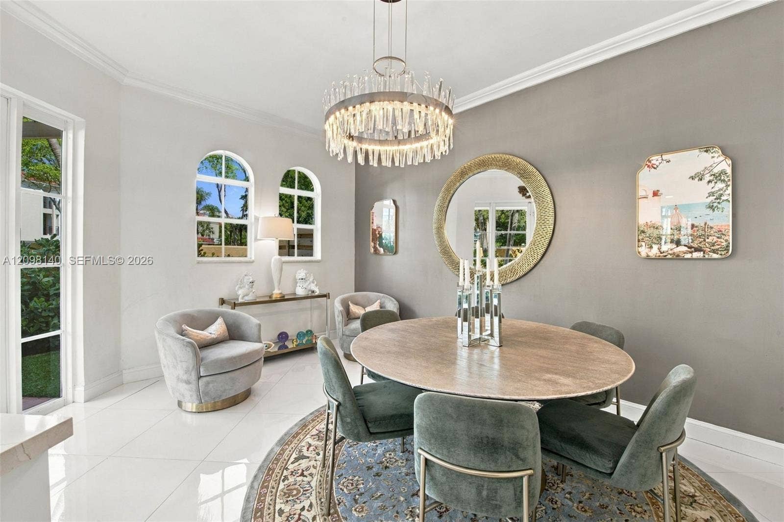 Dining area featuring polished large-format tile flooring, arched windows, crown molding, and a crystal drum chandelier