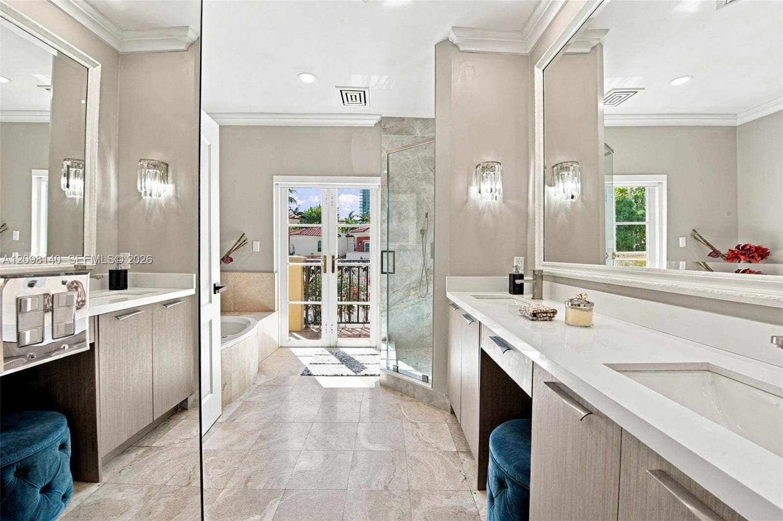 Bathroom featuring dual vanities with light wood-finish cabinetry, quartz countertops, a stone-surround soaking tub, glass-enclosed shower, and French doors