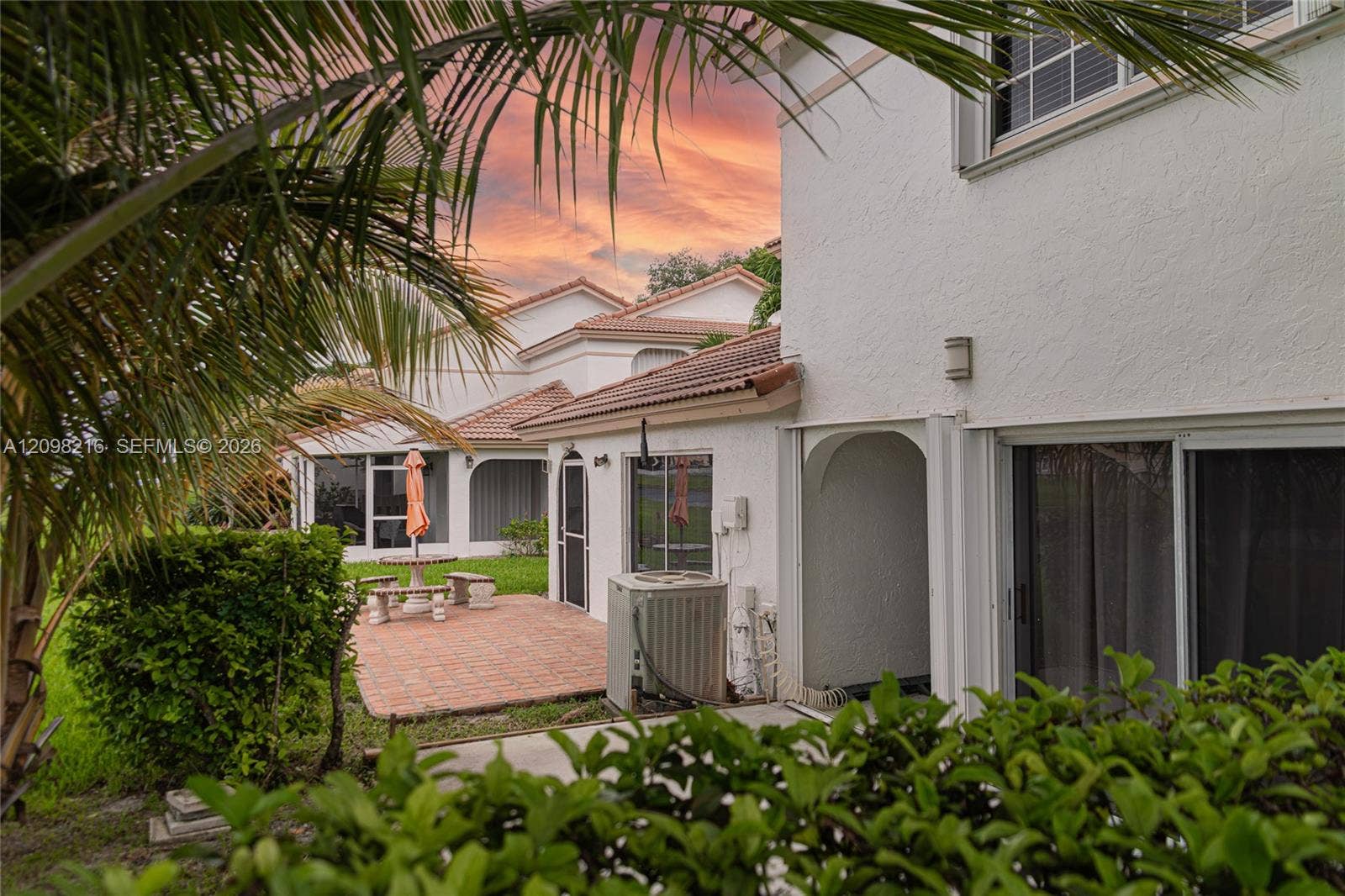 Rear exterior with private patio and lush, layered landscaping.