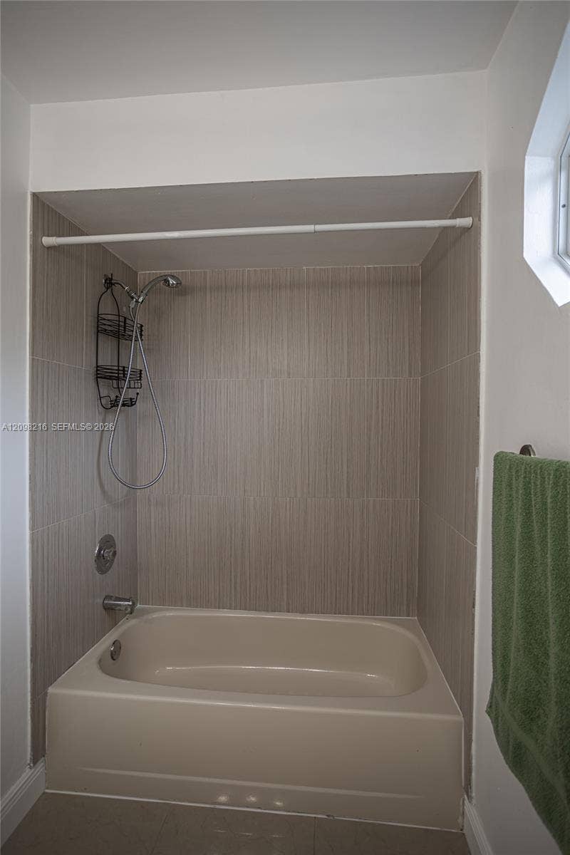 Tub and shower combination finished in neutral tile.
