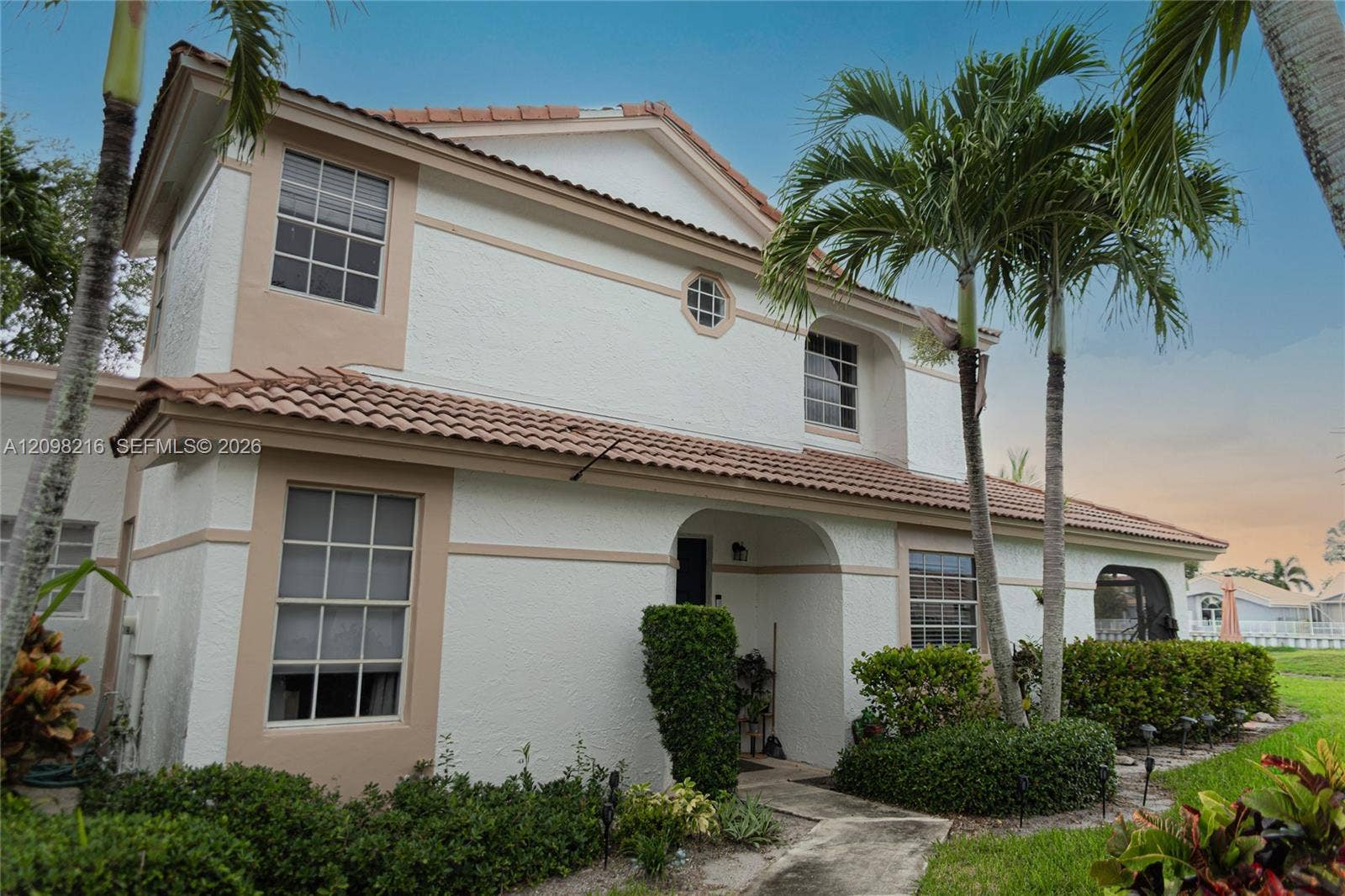 Classic two story Mediterranean style exterior framed by tropical palms.