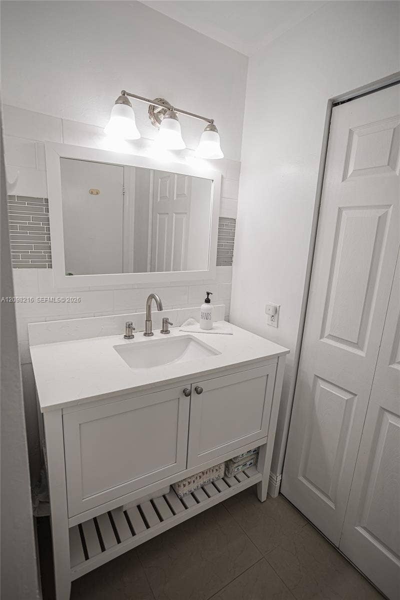White vanity with an open lower shelf and modern lighting.