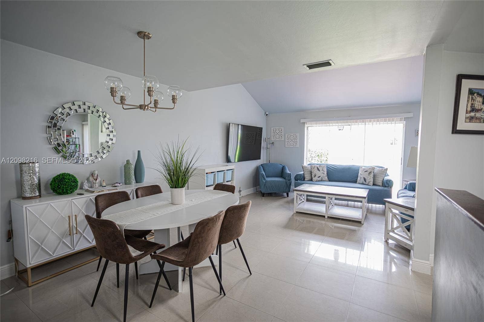 Dining area with a statement chandelier, open to the living room.