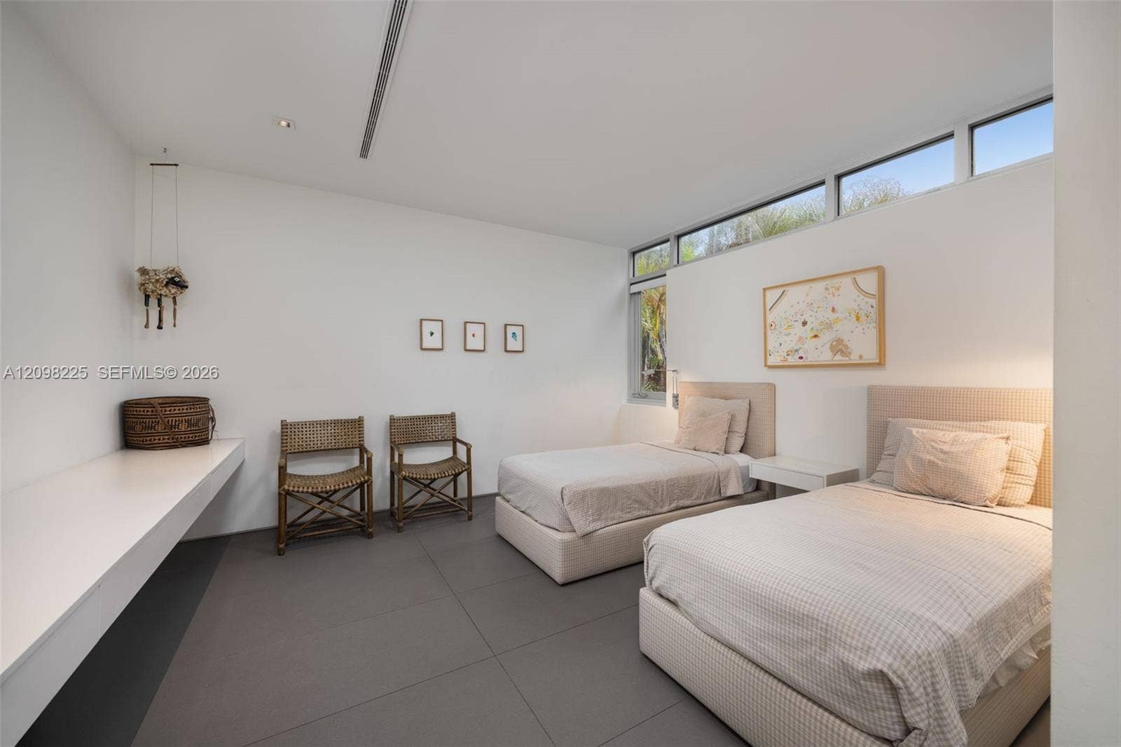 Minimalist room featuring large-format tile flooring, high ceilings with integrated lighting, and a built-in wall-mounted desk