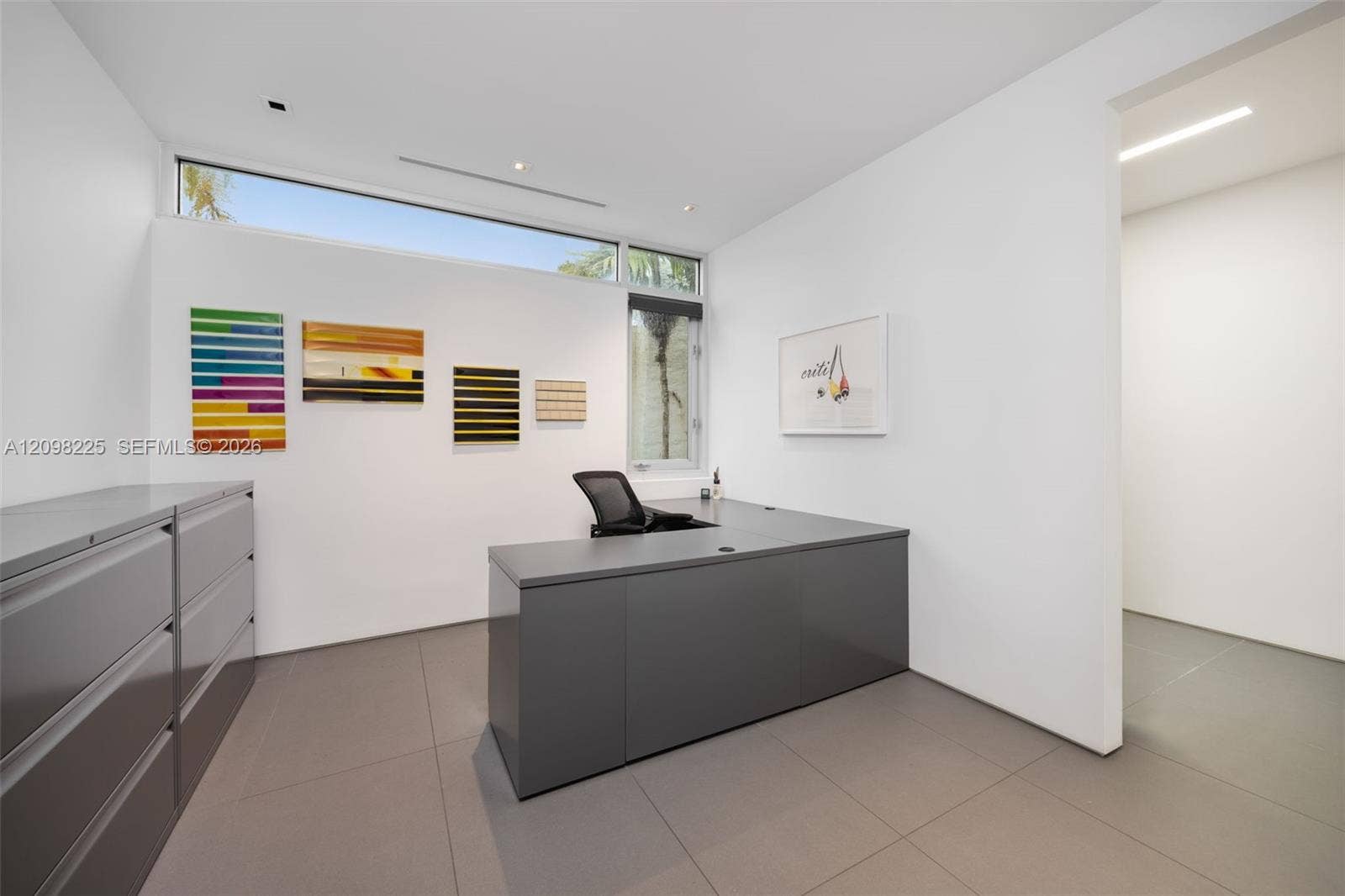 Minimalist room featuring large-format neutral tile flooring, high ceilings with recessed linear lighting, and clerestory windows