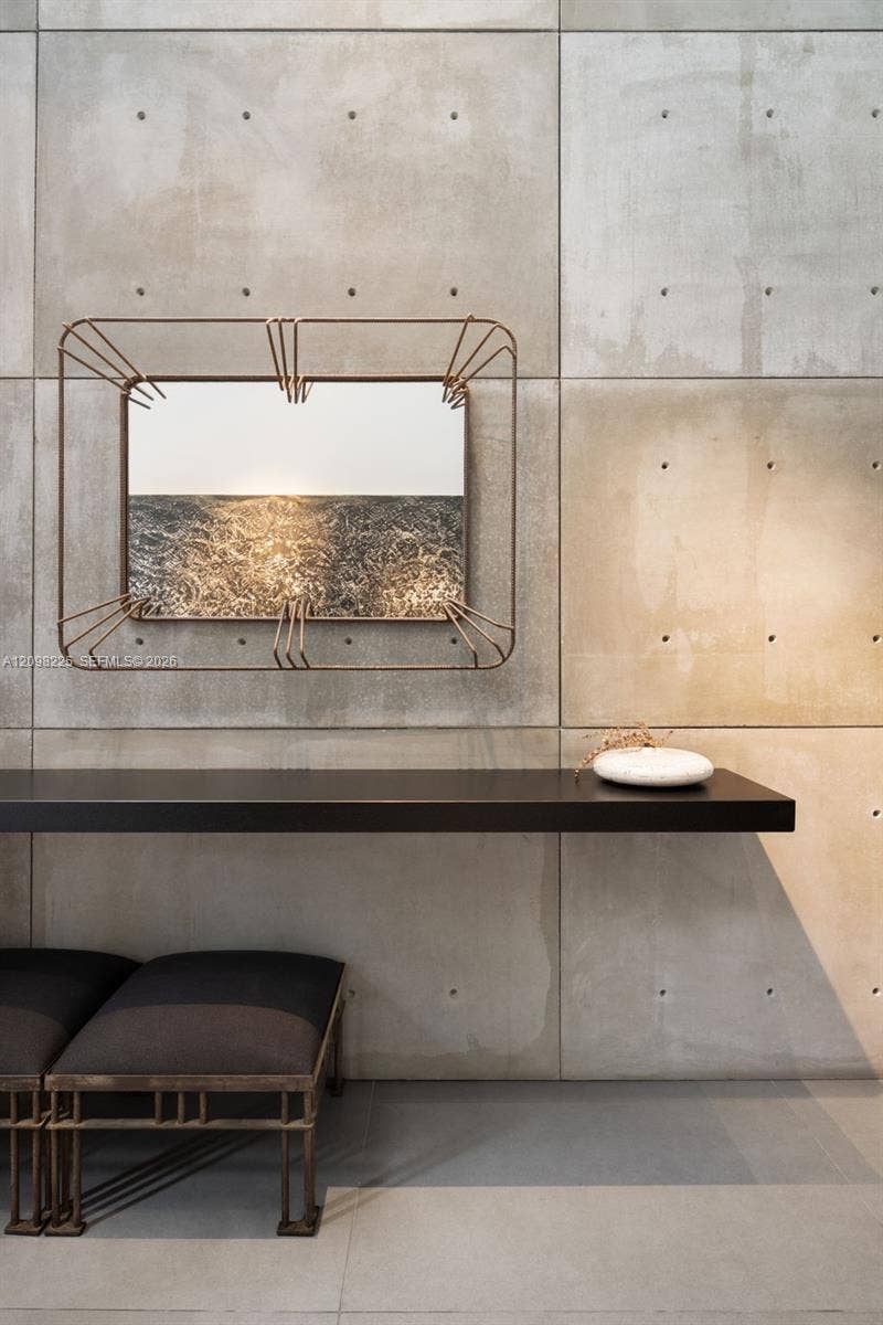 Exposed concrete panel walls, linear matte black floating shelf, and industrial-style metal-framed rectangular mirror